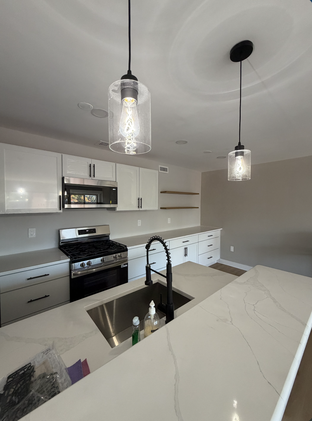 Remodeled kitchen with white cabinets, quartz island, and pendant lighting